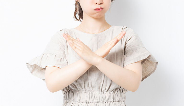 バツの手をする女性