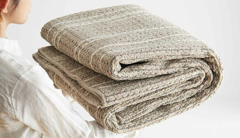 洗えるラグを畳んで運ぶ女性